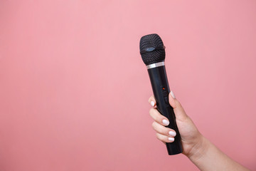 microphone in female hand on pink background