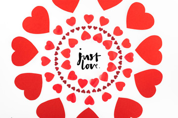 elevated view of circles made of red heart symbols isolated on white, st valentine day concept with "just love" lettering