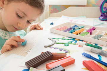 girl with plasticine at the table. Development of small motor skills of children. Child sculpts from plasticine