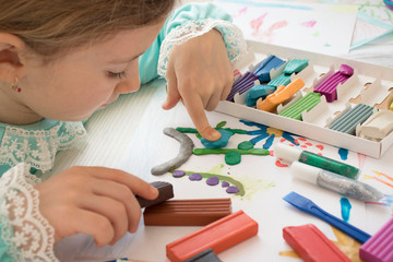 girl with plasticine at the table. Development of small motor skills of children. Child sculpts from plasticine