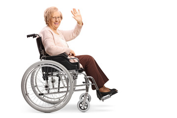 Obraz na płótnie Canvas Senior woman in a wheelchair smiling at the camera and waving