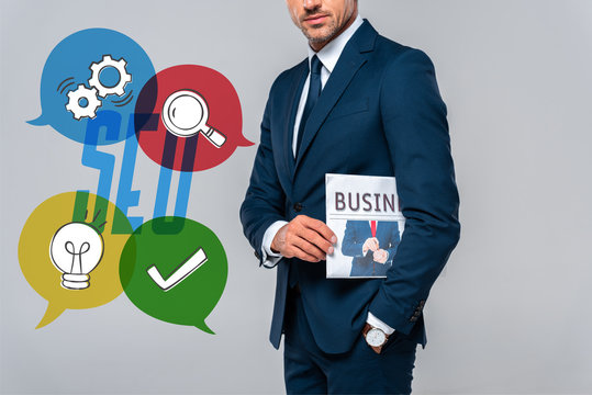 cropped image of businessman holding newspaper isolated on grey with seo icons