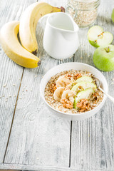 Healthy breakfast oatmeal with nuts ad fruits - apple, banana, walnuts, With milk on wooden background copy space
