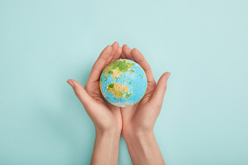 top view of woman holding planet model on turquoise background, earth day concept - obrazy, fototapety, plakaty
