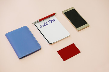 Business desk with wallet, notepad with inscription credit plan, a smartphone and a credit card. Working desk table concept.