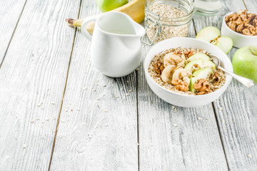 Healthy breakfast oatmeal with nuts ad fruits - apple, banana, walnuts, With milk on wooden background copy space