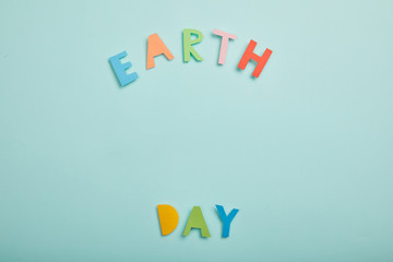 top view of colorful paper letters on turquoise background, earth day concept