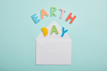 top view of colorful paper letters and and envelope on turquoise background, earth day concept