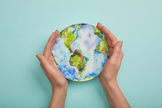top view of woman holding planet picture on turquoise background, earth day concept