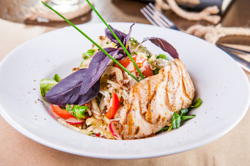 Roasted chicken salad with greenery and vegetables on the white plate. Selective focus, copy space.