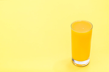 Fresh orange juice on yellow background