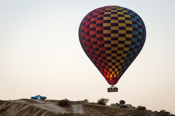 Colorful hot air balloons and an old blue car in Cappadocia.