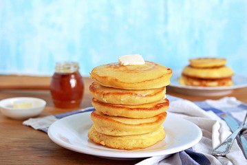 Fototapeta na wymiar Cornmeal pancakes on a white plate. Served with butter and honey or maple syrup.