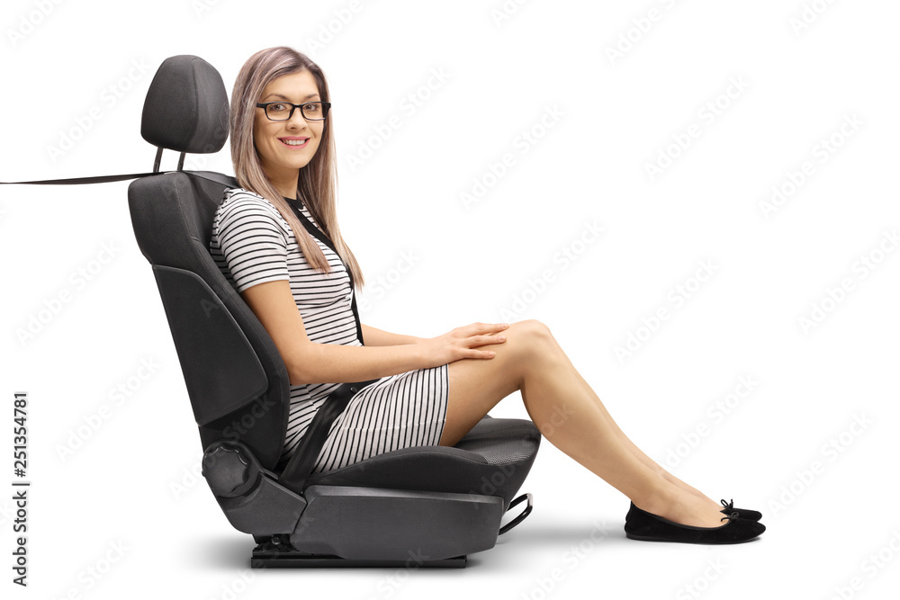 Poster young female passenger in a car seat with a fastened seatbelt smiling at the camera