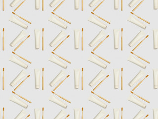 bamboo toothbrushes and toothpaste in tubes in different directions on grey background, seamless background pattern