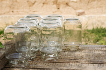 Three-liter glass banks on wooden boards. Glass jars for home pickles in the courtyard of a village house