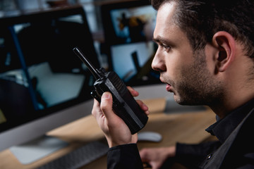 selective focus of guard holding walkie-talkie at workspace