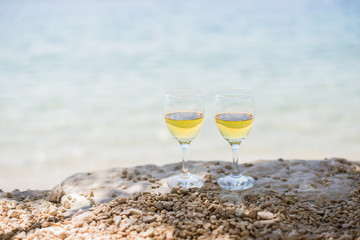 Two glasses of white wine at the beach with sea at background