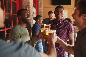 Group Of Male Friends Meeting In Sports Bar Making Toast Together