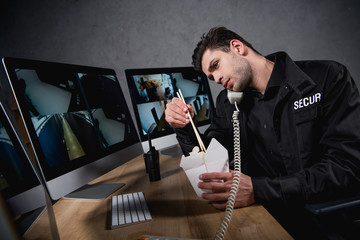 guard in uniform eating junk food and talking on telephone