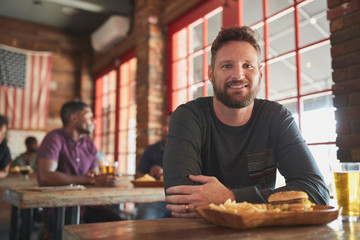 Portrait Of Man In Sports Bar Eating Burger And Fries