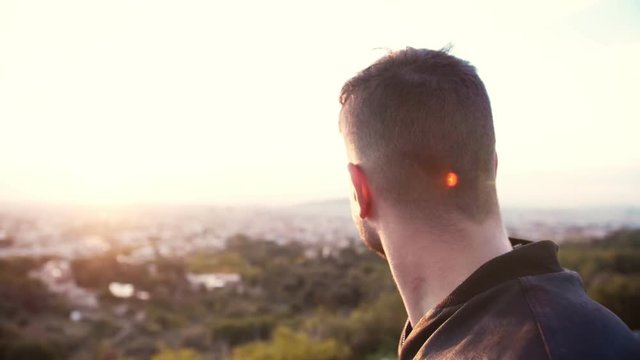 Backside or back of head or neck of brave masculine serious man who observing cityscape of beautiful city early in the morning during sunrise or sunset, searching problems Lens flare of the autumn sun