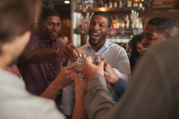Group Of Male Friends On Night Out Drinking Shots In Bar Together
