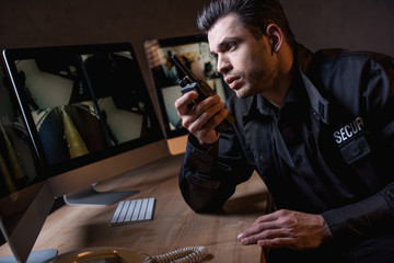 handsome guard in uniform talking on walkie-talkie at workplace