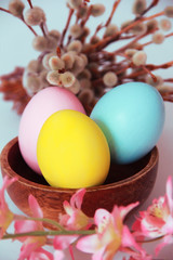 Obraz na płótnie Canvas pink yellow blue eggs against a background of willow and flowers for the Easter holiday