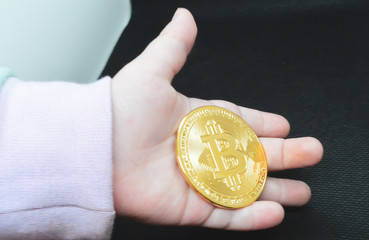 Bitcoin coin in child's hand, close-up