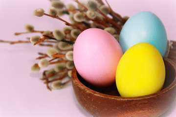 Fototapeta na wymiar pink yellow blue eggs against a background of willow and flowers for the Easter holiday