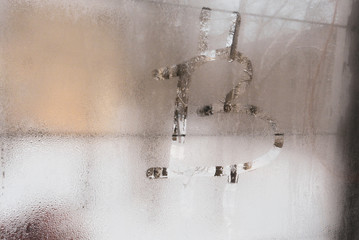 Bitcoin symbol on the misted glass of a wooden old window