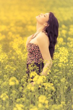 Happy beautiful girl in free summer love of youth wellbeing. Attractive young woman enjoying the warm sunny sun in nature rapeseed field takes time feeling sustainability and contemplation