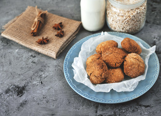 Oat cookies in blue plate with ingredients on wooden background.