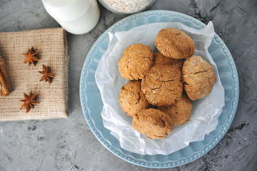 Oat cookies in blue plate with ingredients on wooden background.