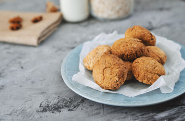 Oat cookies in blue plate with ingredients on wooden background.