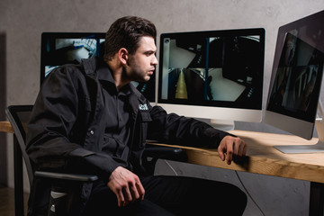 focused guard in uniform looking at computer monitor at workspace