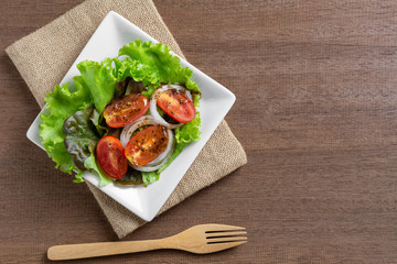 top view of vegetable salad in a ceramic dish on wooden table. homemade style healthy food concept.