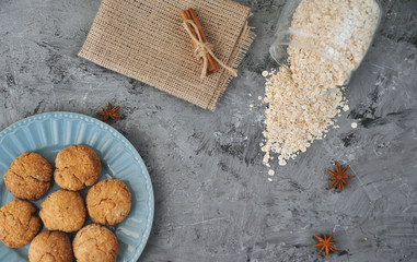 Oat cookies in blue plate with ingredients on wooden background.