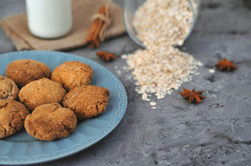 Oat cookies in blue plate with ingredients on wooden background.