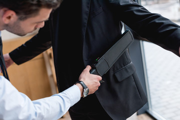  cropped view of guard using metal detector
