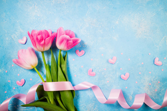 Spring holiday background. Flowers for Valentine's, Mother's or Women's Day. Pink tulips flowers on blue background. Top view, copy space