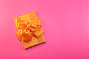 The gift is packed and decorated with a yellow bow on a pink background with copy space. Flat lay, top view. copy space