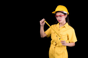 Woman architect wearing a protective yellow helmet holding measuring tape on black background. Working concept.