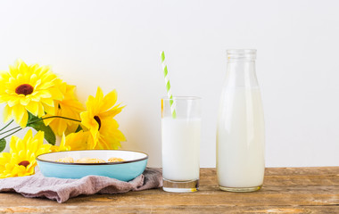A glass of milk with milk bottle and cookies on wooden table
