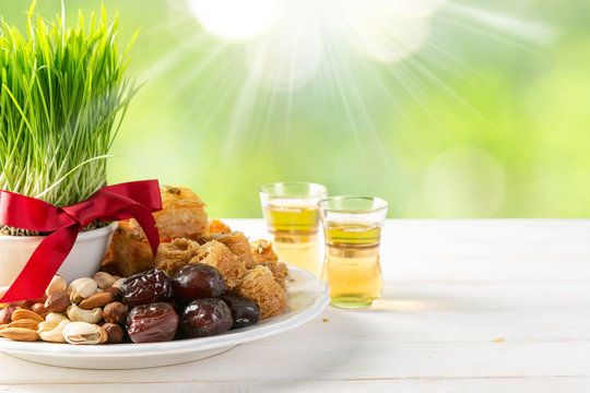 Nowruz holiday concept - grass, baklava sweets, nuts and seeds, copy space