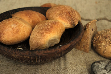 Food photography. Bread on a wooden plate. Bread on a brown background on the table. Different types of baked bread on a dark brow table