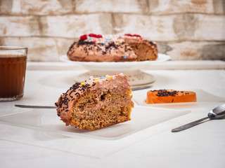 A piece of homemade cake in the foreground on a glass plate