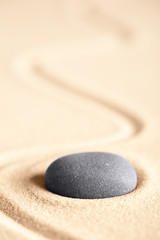 Fototapeta na wymiar Zen meditation stone for concentration and relaxation giving energy and inspiration. Concept for balance, harmony hope and purity. Round rock on textured sand background with room for copy space.