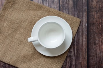white cup of coffee and sackcloth on wooden table.